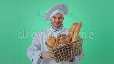 绿墙画室的面包师，一个笑容满面的男人，手里拿着一个带着新鲜面包的篮子，他直视着摄像机